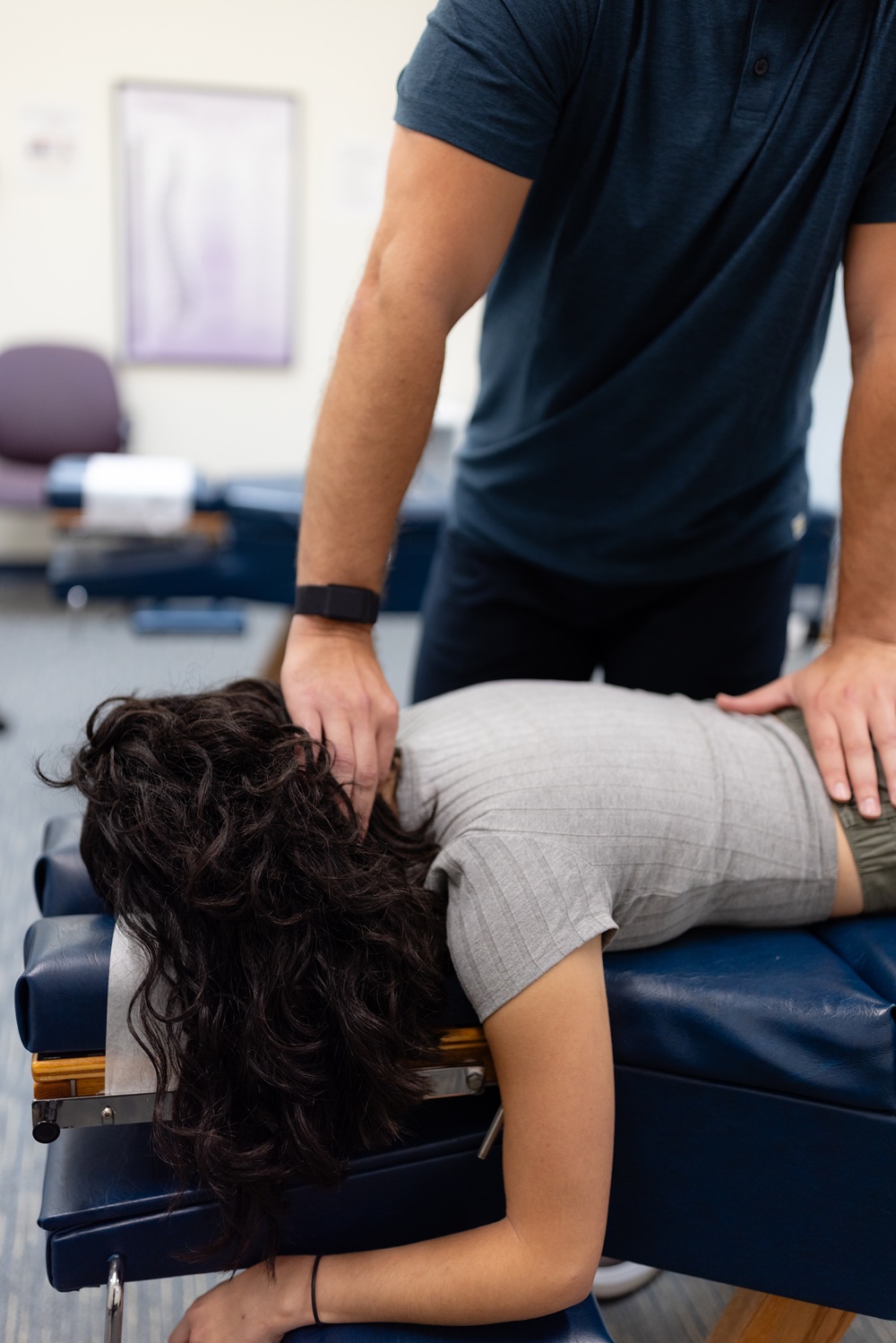 Chiropractor performing a neck and lower back adjustment on a patient lying on a treatment table 