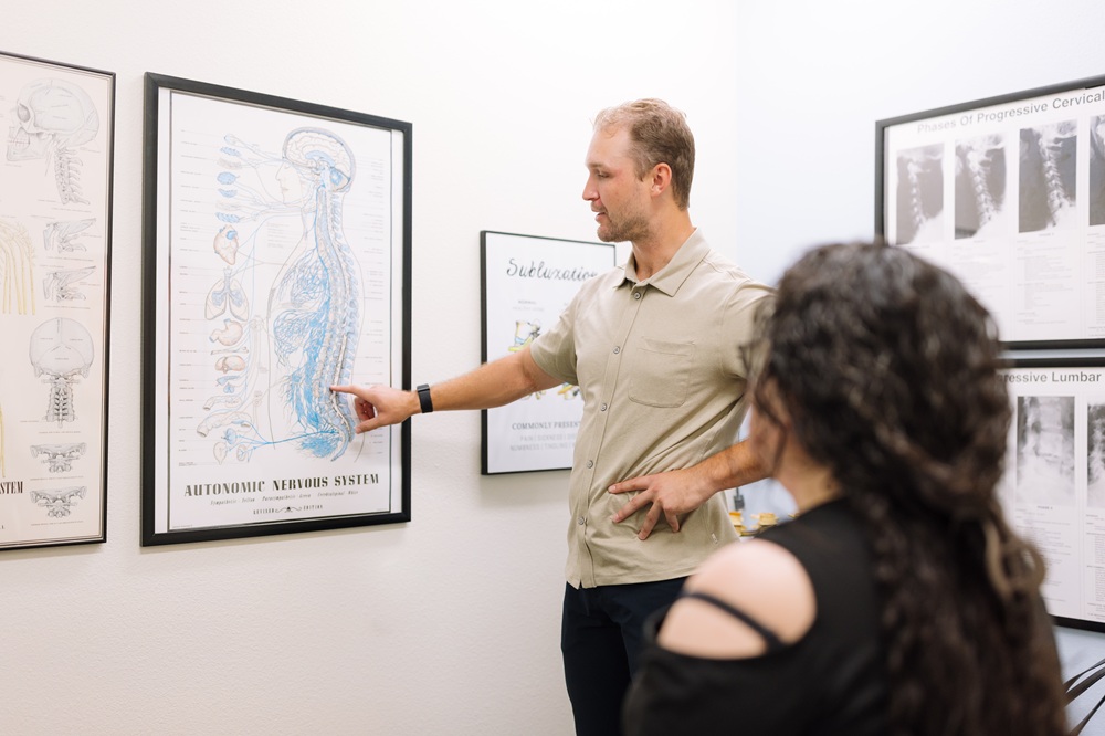 Chiropractor explaining the autonomic nervous system to a patient using a wall chart in Mission Valley, San Diego