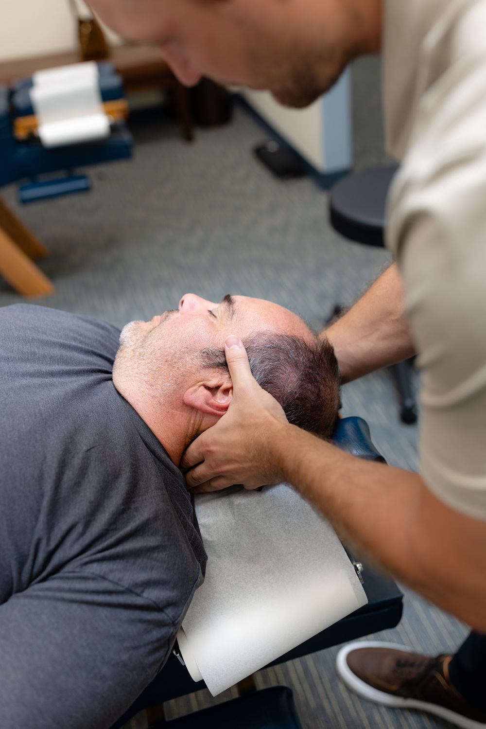 Cervical adjustment for neck pain relief in San Diego, CA Chiropractor performing a manual neck adjustment on a patient lying on a treatment table