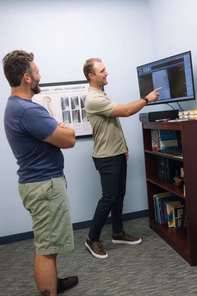 Reviewing spinal imaging during a chiropractic consultation Chiropractor reviewing spinal x-ray images on a monitor with a patient in Mission Valley, San Diego